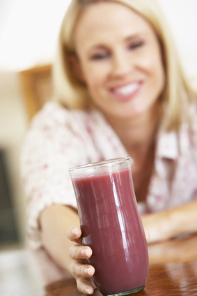 Mid-Adult Woman Reaching for a Fresh Berry Smoothie